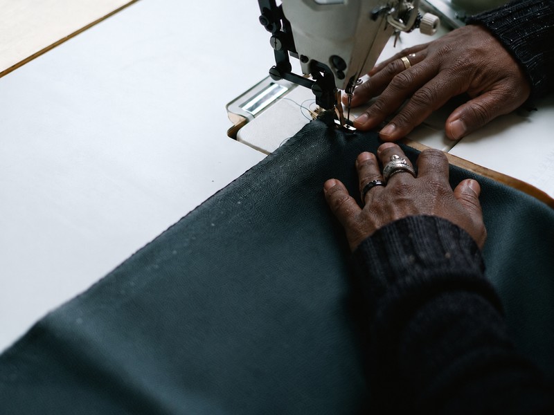 Hands stitching a dark garment at a sewing machine