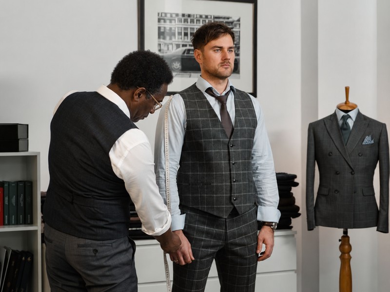Tailor measuring a suit during a fitting